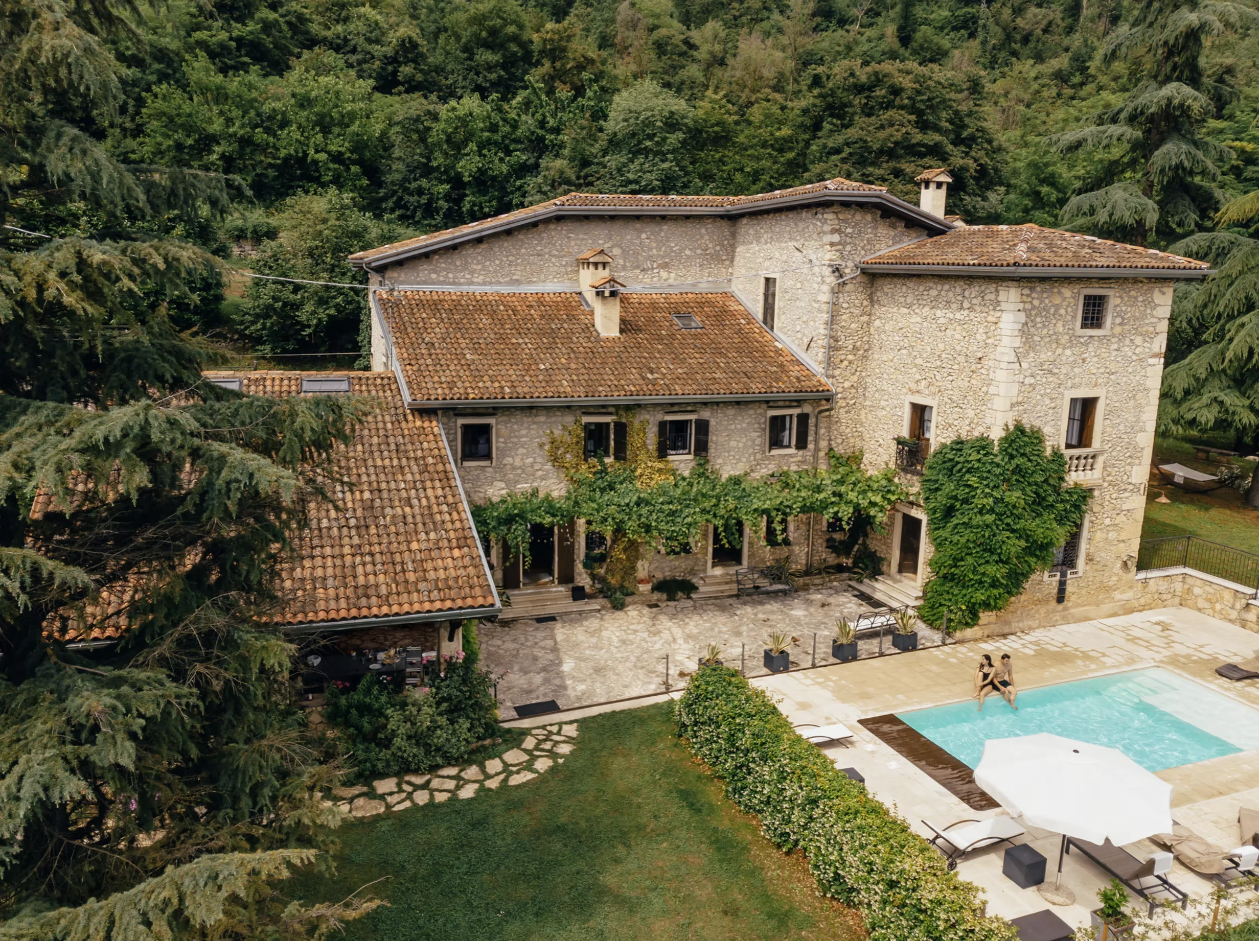 Stone house beside a swimming pool surrounded by trees