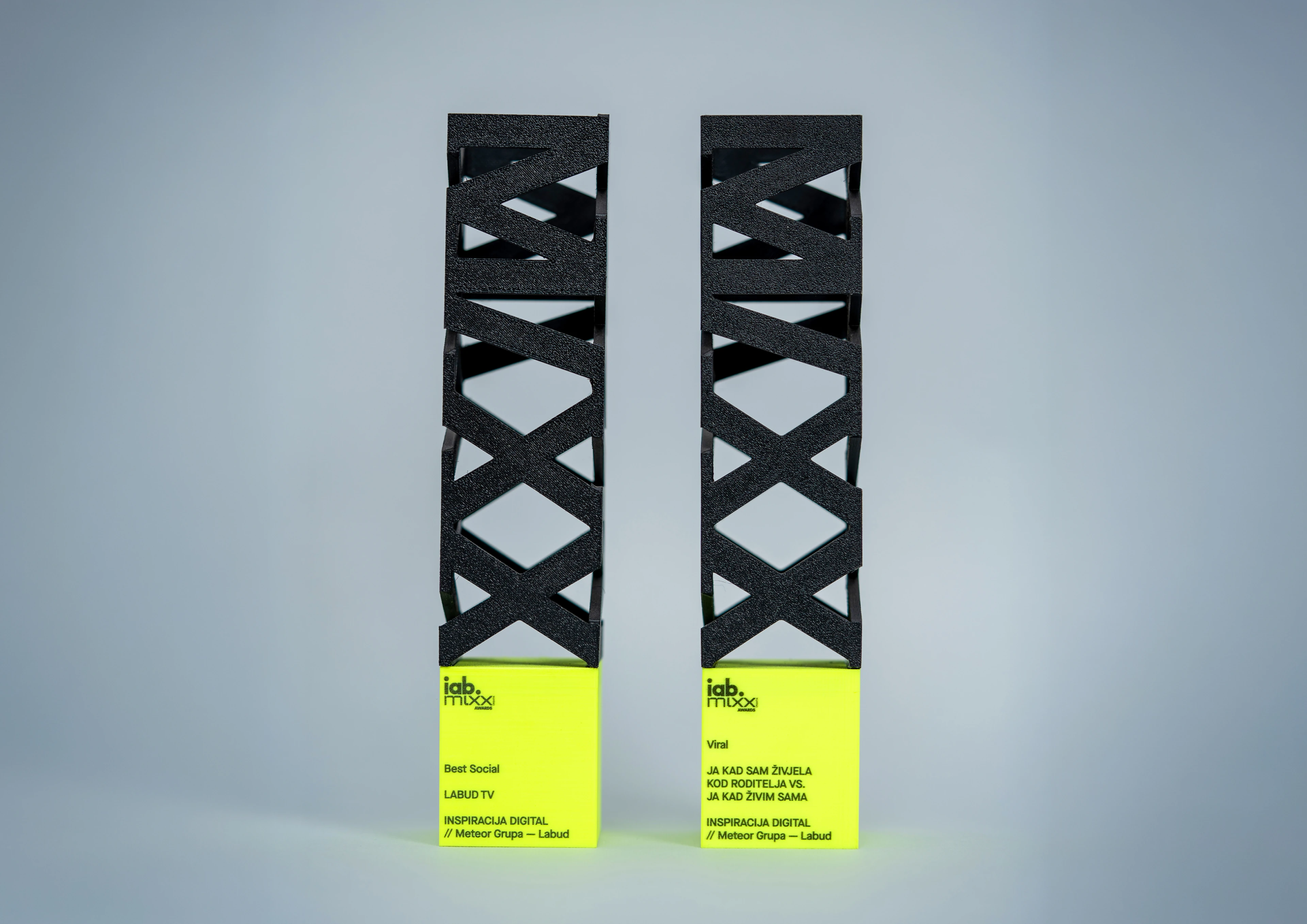 Two black and fluorescent yellow MIXX Awards trophies for Labud TV.